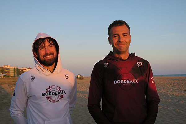 twee mannen met 33tours-hoodies op het strand
