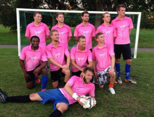 team van voetballers poseren in roze poloshirts
