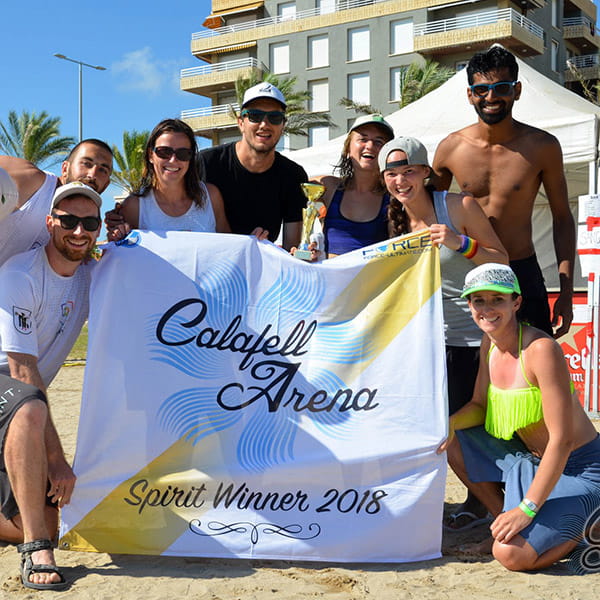 team poseren op strand met calafell witte en gele vlag