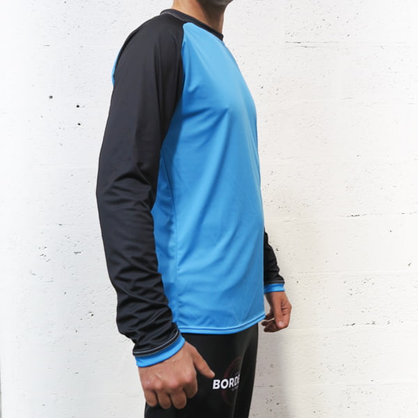 side view of the torso of a man wearing a blue and black raglan longsleeved jersey