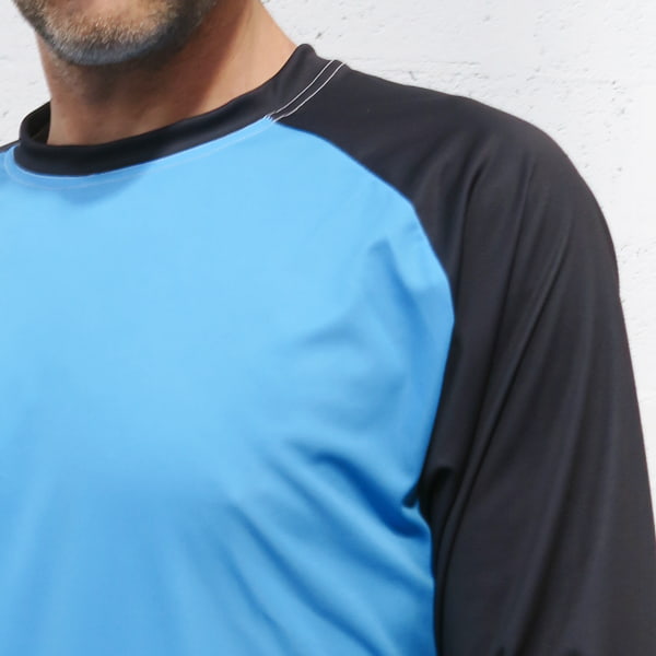 schouder van een man met blauw en zwaart langemouwen raglan-shirt