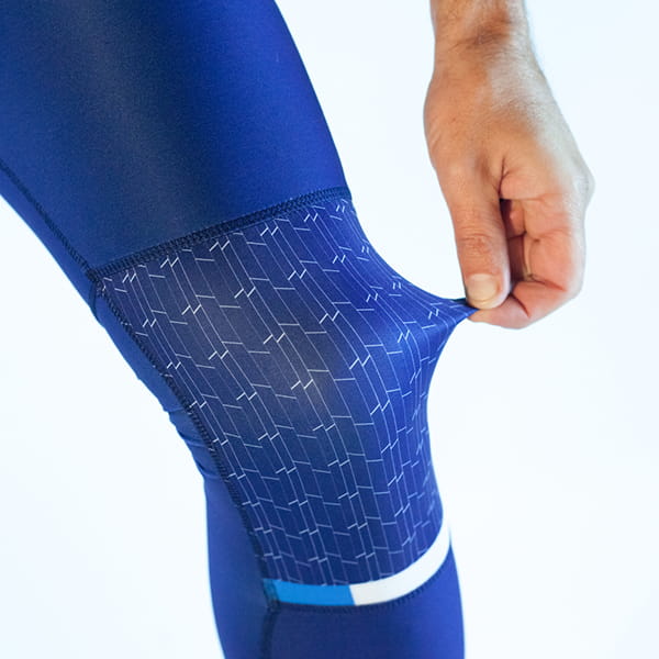main tirant un tissu extensible au niveau du genou d'un legging bleu