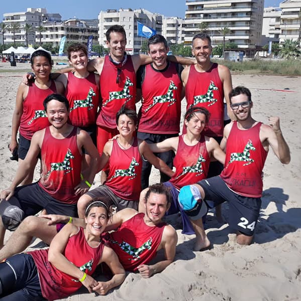 équipe sportive posant sur la plage portant des maillots rouges