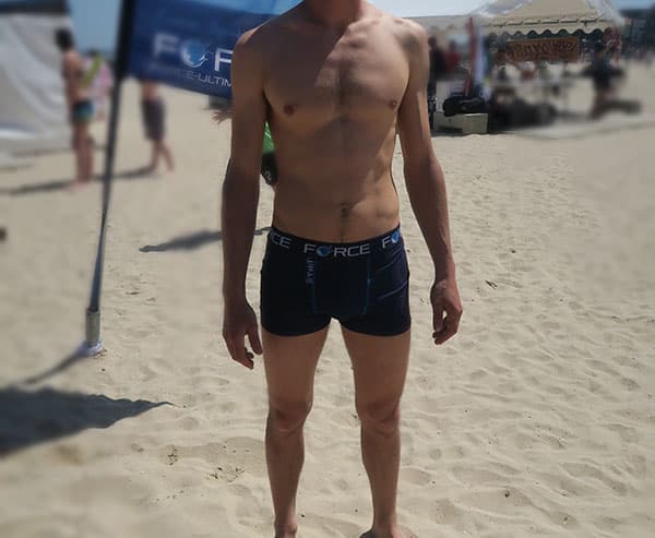 lichaam van een man met blauw gesublimeerd ondergoed op het strand