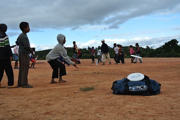 duffle bag on dirt ground with kids playing around