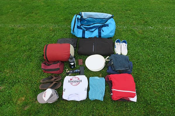 light blue bag and clothes neatly arranged on grass