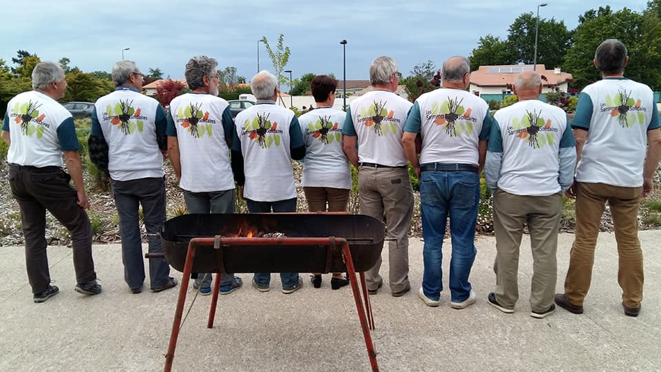 group of men wearing the same t-shirt standing behind a barbecue
