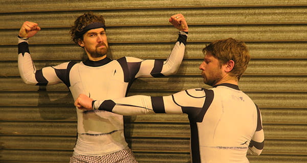 two men flexing wearing a white compression top with long sleeves