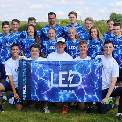 team posing on grass field with blue jerseys and blue led flag