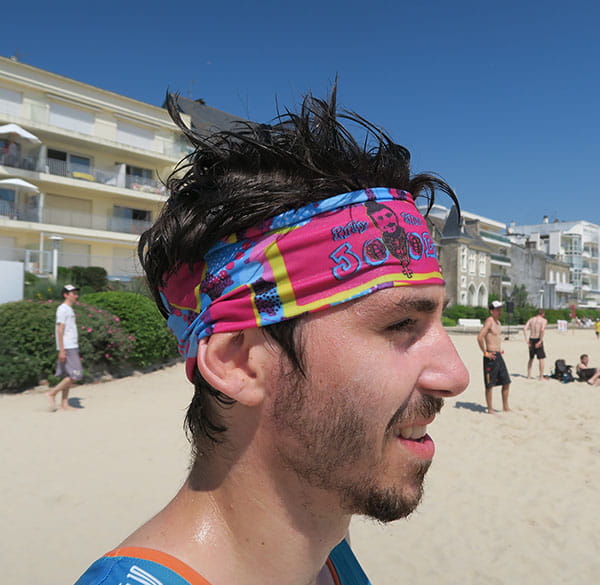 right side view of head of man wearing a pink and blue headband at the beach