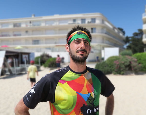 man wearing a green and orange headband and colorful jersey at the beach