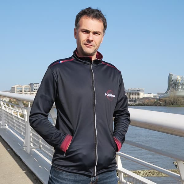 man standing on a bridge wearing a black sport jacket hands in pockets