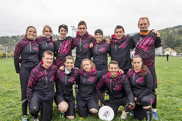 team poseren op grasveld met zwarte en roze gesublimeerde hoodies