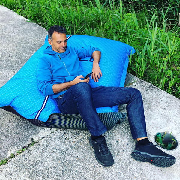 man sitting on blue giant cushion watching his phone