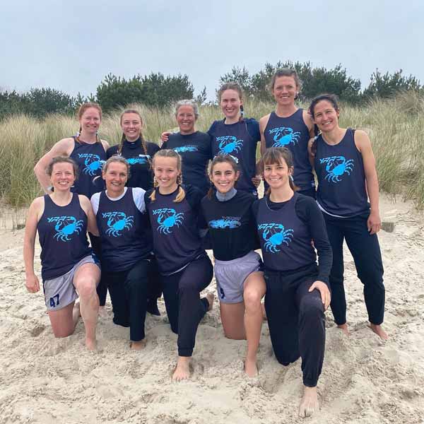 sport team posing on beach wearing red singlets