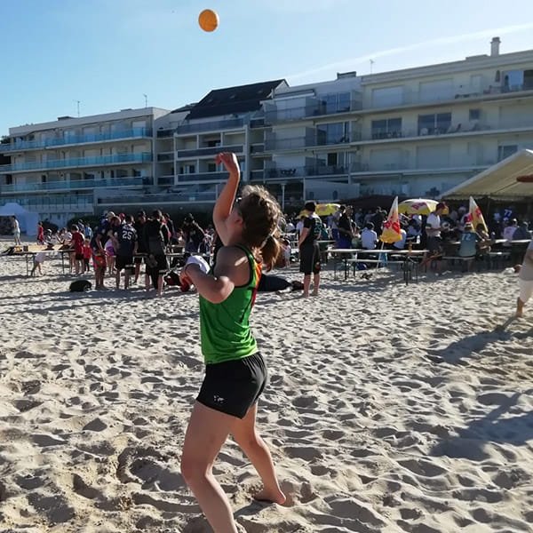 side view of woman on beach playing spikeball